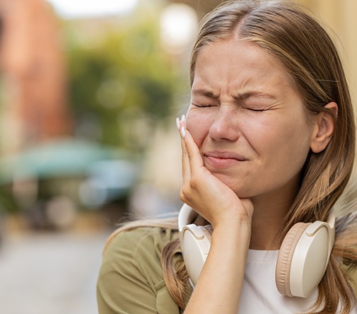 Woman experiencing toothache while walking outside