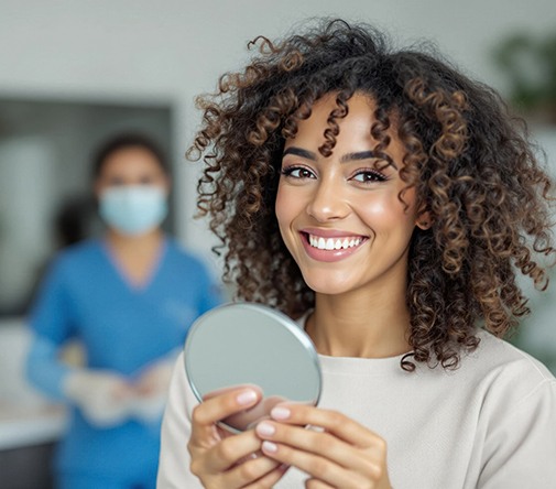 Woman smiling while holding small mirror