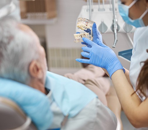 Dental team member showing implant model to patient