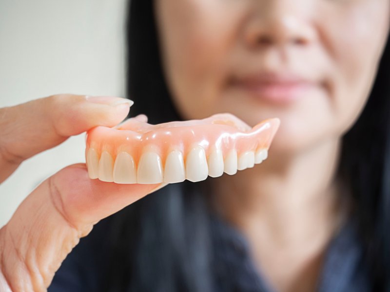 dentist holding out pair of dentures