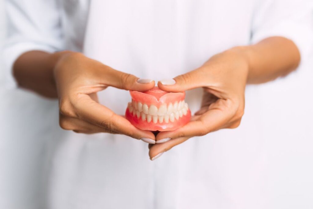 A woman holding a pair of dentures.